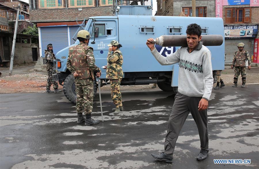 A Kashmiri woman and her child walk past Indian paramilitary troopers during the curfew in Srinagar, summer capital of Indian-controlled Kashmir, on July 18, 2016. 