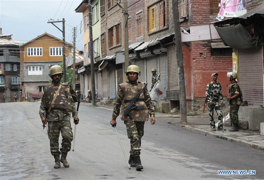 A Kashmiri woman and her child walk past Indian paramilitary troopers during the curfew in Srinagar, summer capital of Indian-controlled Kashmir, on July 18, 2016. 