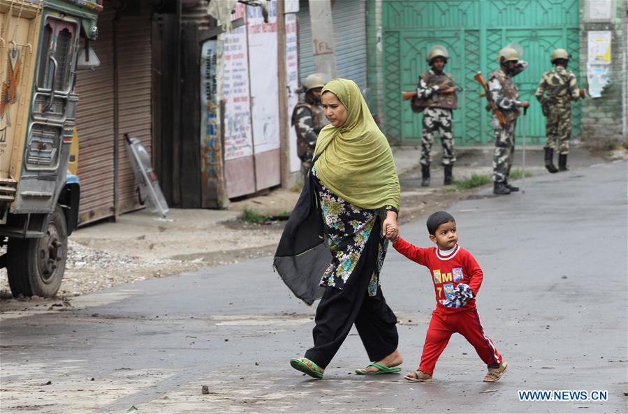 A Kashmiri woman and her child walk past Indian paramilitary troopers during the curfew in Srinagar, summer capital of Indian-controlled Kashmir, on July 18, 2016. A Kashmiri woman and her child walk past Indian paramilitary troopers during the curfew in Srinagar, summer capital of Indian-controlled Kashmir, on July 18, 2016.