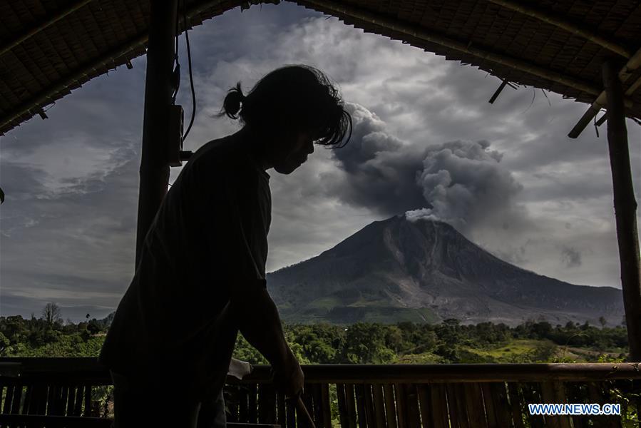 A woman watches the eruption of Mount Sinabung at Tiga Pancur village in Karo district, North Sumatra, Indonesia, July 24, 2016. A woman watches the eruption of Mount Sinabung at Tiga Pancur village in Karo district, North Sumatra, Indonesia, July 24, 2016.