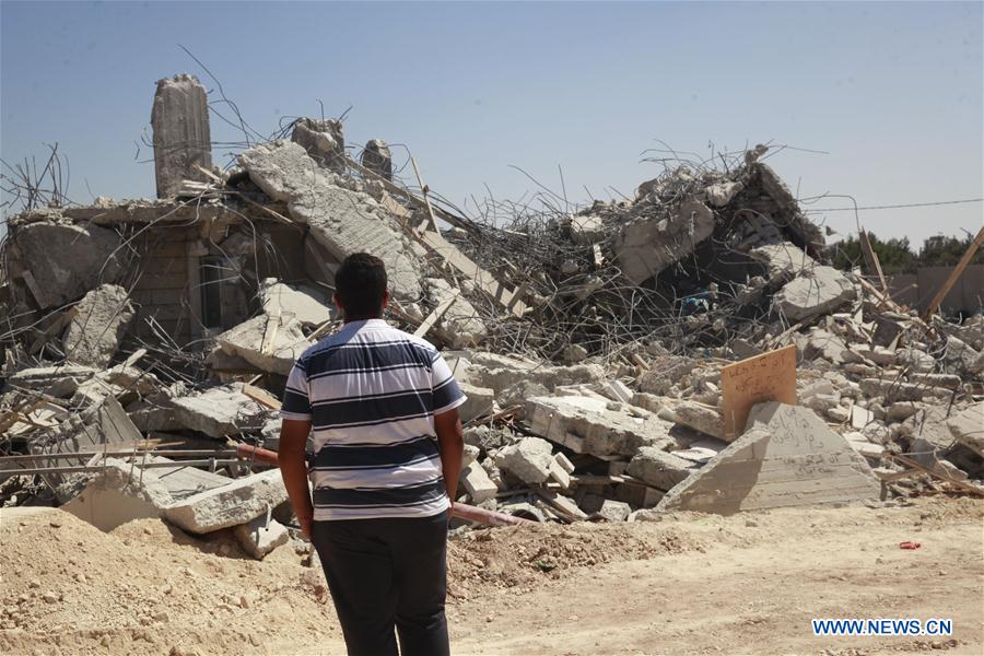 Palestinians stand by the rubble of a house which was demolished by Israeli army bulldozers in the village of Qalandiya, next to Israel's controversial separation barrier, near the West Bank town of Ramallah on July 26, 2016. Palestinians stand by the rubble of a house which was demolished by Israeli army bulldozers in the village of Qalandiya, next to Israel's controversial separation barrier, near the West Bank town of Ramallah on July 26, 2016.
