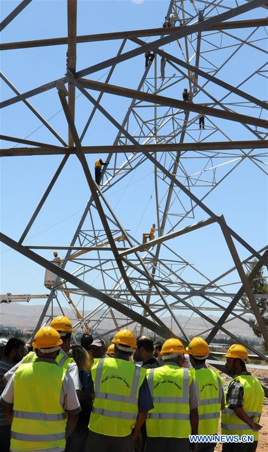 Electricity workers fix high-voltage power lines in Dimas, countryside of Damascus, capital of Syria, on July 27, 2016.