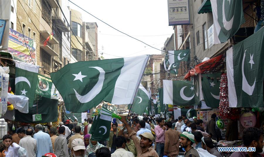 A Pakistani vendor (L) sells flags on a street ahead of the country's Independence Day in eastern Pakistan's Lahore, Aug. 11, 2016. 