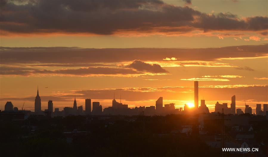 An airplane flies over Manhattan as the sun sets in New York, the United States, Sept. 7, 2016.