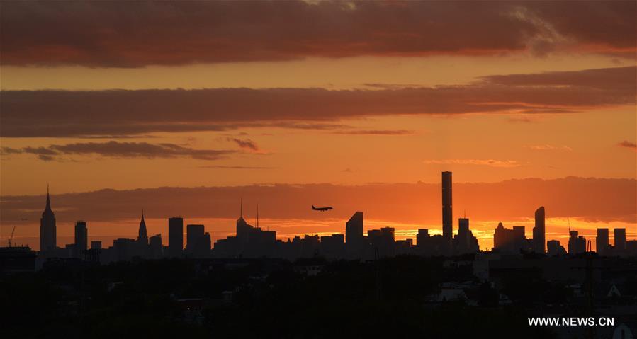 An airplane flies over Manhattan as the sun sets in New York, the United States, Sept. 7, 2016.