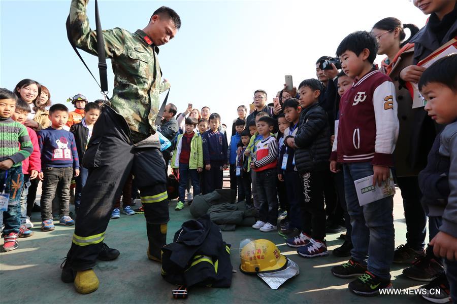 Students and their parents try fire extinguishers under the guidance of firefighters during a fire fighting public event in Huaibei, east China's Anhui Province, Nov. 5, 2016