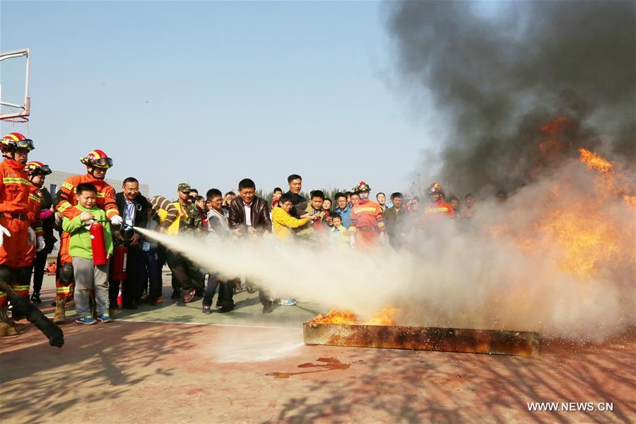 Students and their parents try fire extinguishers under the guidance of firefighters during a fire fighting public event in Huaibei, east China's Anhui Province, Nov. 5, 2016