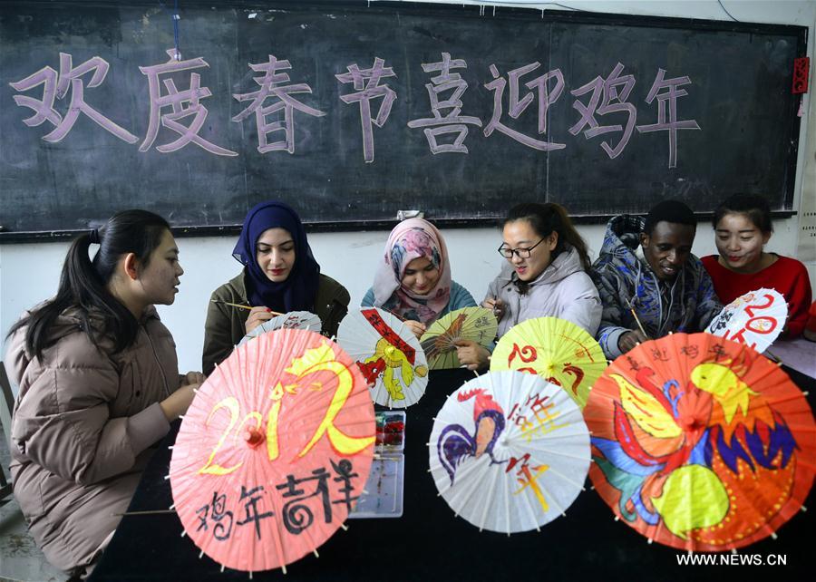 Volunteers from the Academy of Arts of Liaocheng University and students from Jordan and Ethiopia on Sunday painted patterns involving rooster on oil-paper umbrellas to greet the upcoming Chinese lunar New Year of Rooster, which falls on Jan. 28 this year.