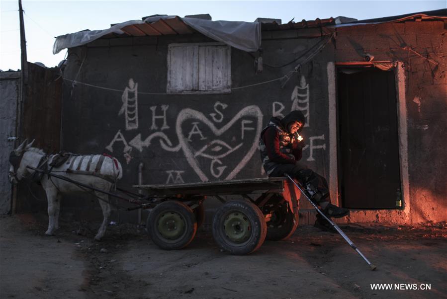 Palestinian refugees warm themselves in front of a fire outside their house during a power outage in Al Zaitun neighbourhood, east of Gaza City, on Jan. 11, 2017. (Xinhua/Wissam Nassar)