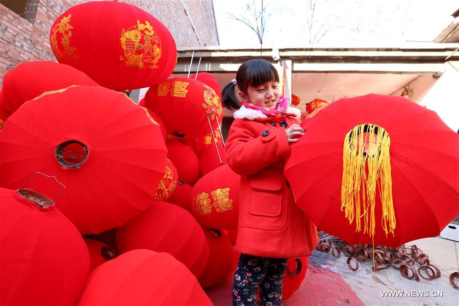 A little girl plays with a red lantern in a lantern workshop in Beileng Township of Wenxian County, central China's Henan Province, Jan. 12, 2017. Villagers need to keep up with the lantern orders to meet the Spring Festival market demand. The Spring Festival falls on Jan. 28 this year. (Xinhua/Xu Hongxing)