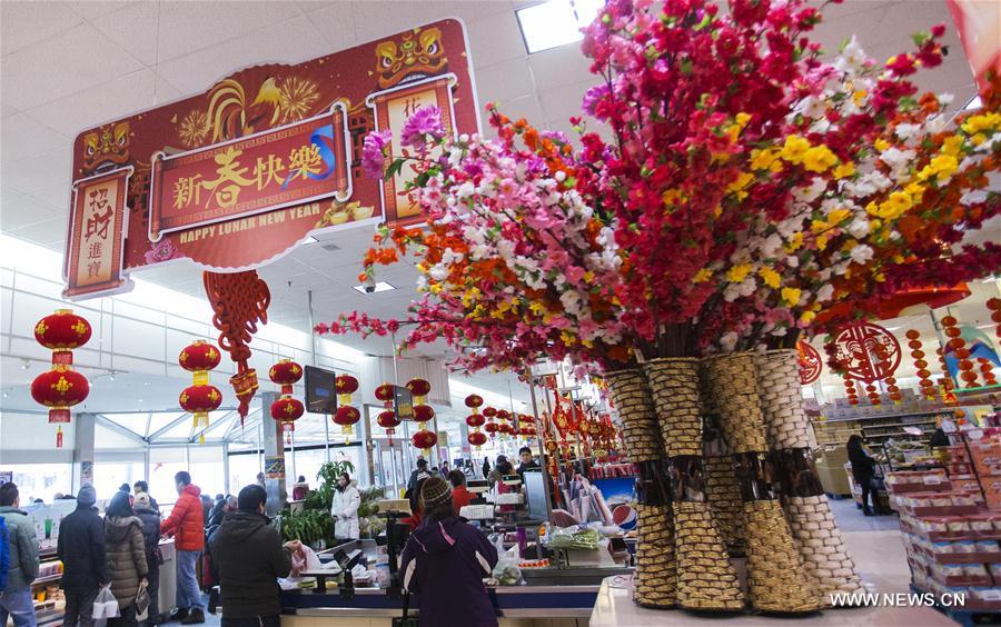 People walk past a shopping window with a rooster sticker celebrating Chinese Lunar New Year, in Toronto, Canada, Feb. 2, 2017. 