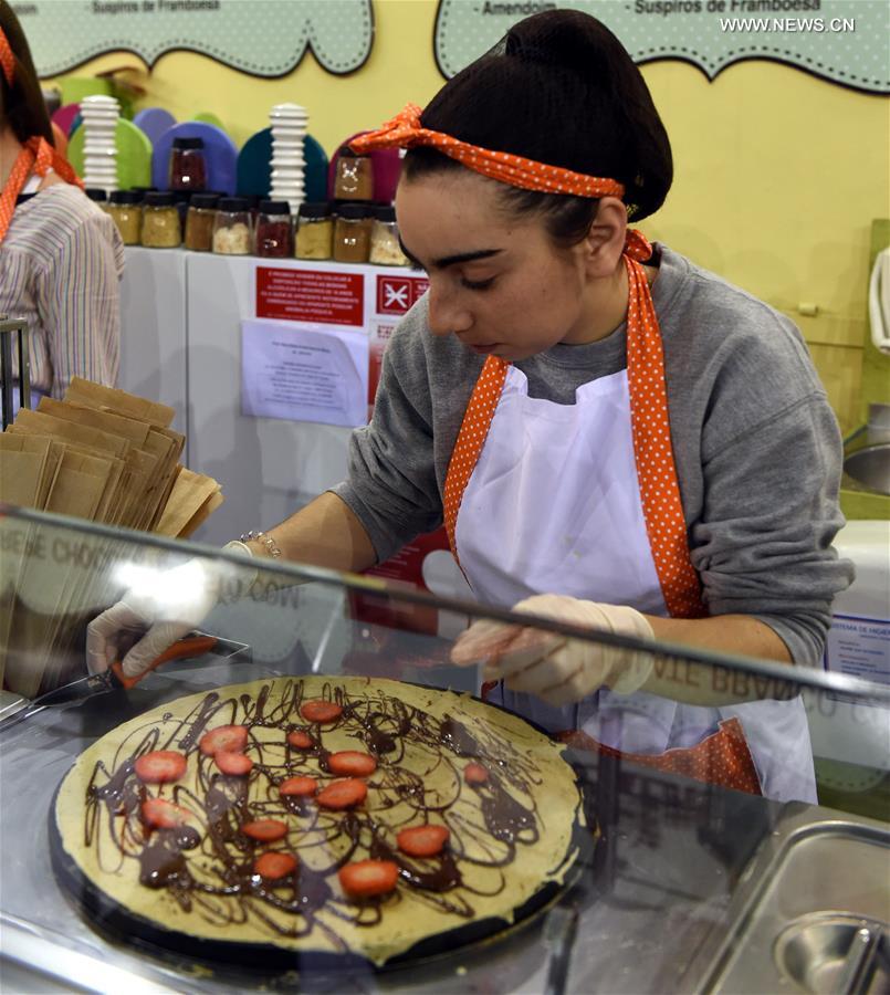 A woman makes chocolate flavour snacks during a chocolate fair at Campo Pequeno Square in Lisbon, capital of Portugal, Feb. 12, 2017.