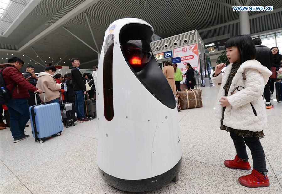 A robot attracts the attention of a child at the Zhengzhou East Railway Station in Zhengzhou, capital of central China's Henan Province, Feb. 15, 2017. 