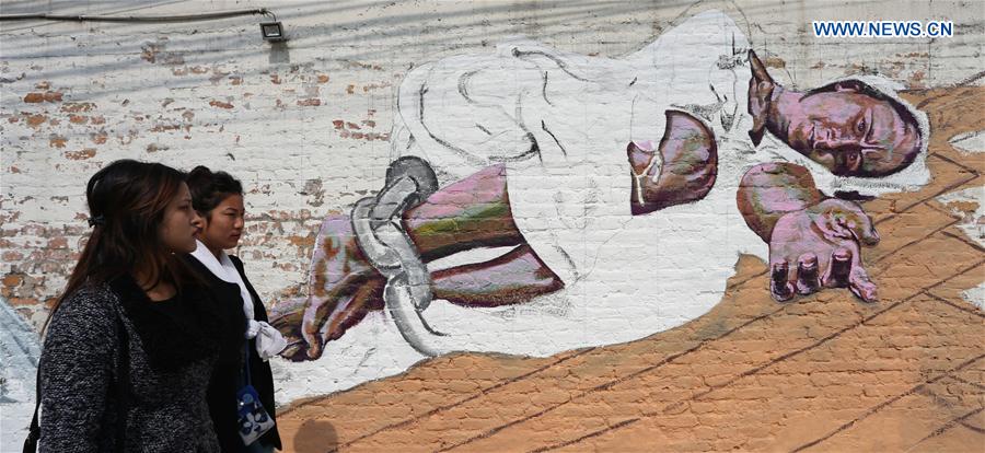 Women walk past a painted wall during the 'Wall of Hope Campaign' in Kathmandu, Nepal, Feb. 17, 2017. 