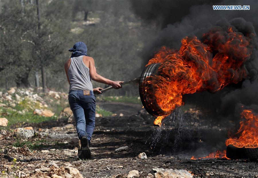 A Palestinian protester burns a tire during clashes with Israeli soldiers after a protest against the expanding of Jewish settlements in Kufr Qadoom village near the West Bank city of Nablus, on Feb. 24, 2017.