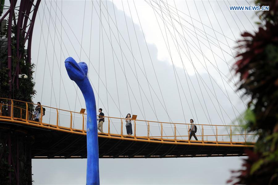 Tourists take photos of a dinosaur statue for the Children's Festival in the Supertree Grove at Singapore's Gardens by the Bay on Feb. 28, 2017. 