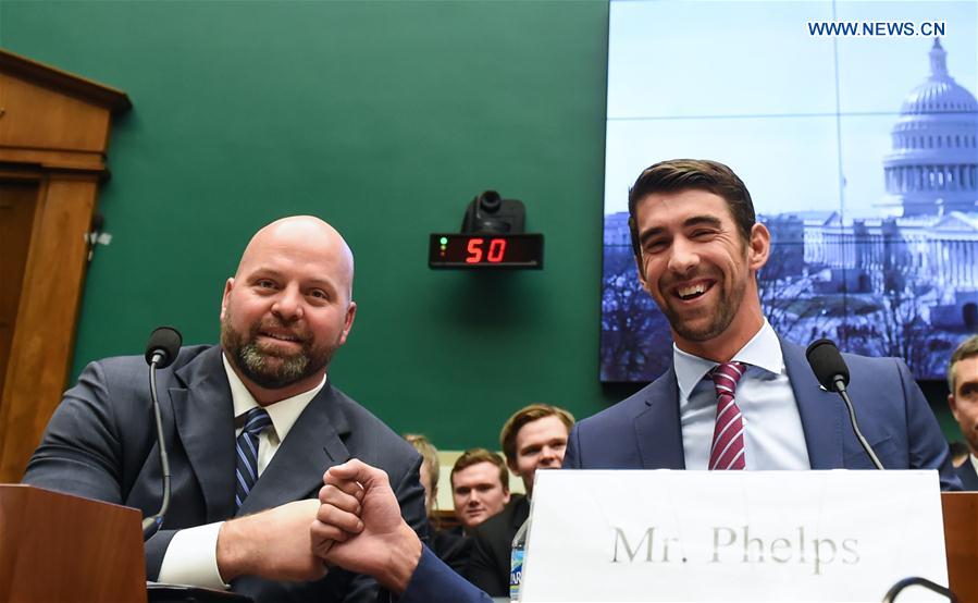 U.S. Olympic gold medalists Michael Phelps (R) and Adam Nelson fist-bump before they testify to the House Energy and Commerce Subcommittee on Oversight and Investigations during a hearing on 'Ways to Improve and Strengthen the International Anti-Doping System' on the Capitol Hill in Washington D.C., the United States, Feb. 28, 2017. 