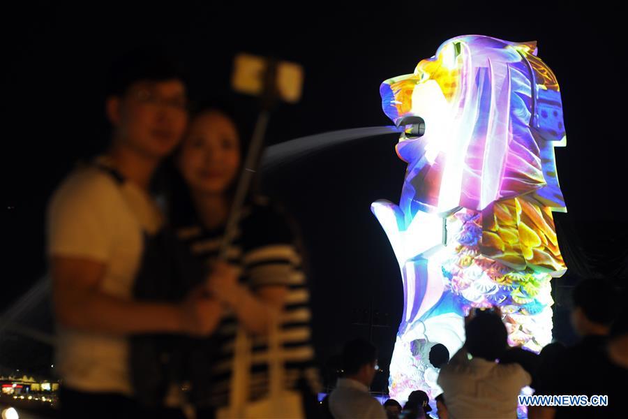 Visitors take photos with a light work at the 'i Light Marina Bay' media preview at Singapore's Marina Bay on March 1, 2017. 