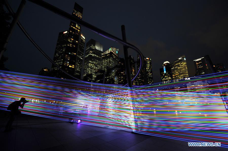 A photographer takes photos of a light work at the 'i Light Marina Bay' media preview at Singapore's Marina Bay on March 1, 2017. 