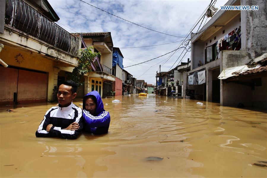People wade through flood water in Bandung, Indonesia, March 8, 2017. During the rainy season, Bandung is often hit by intensive rainfall.