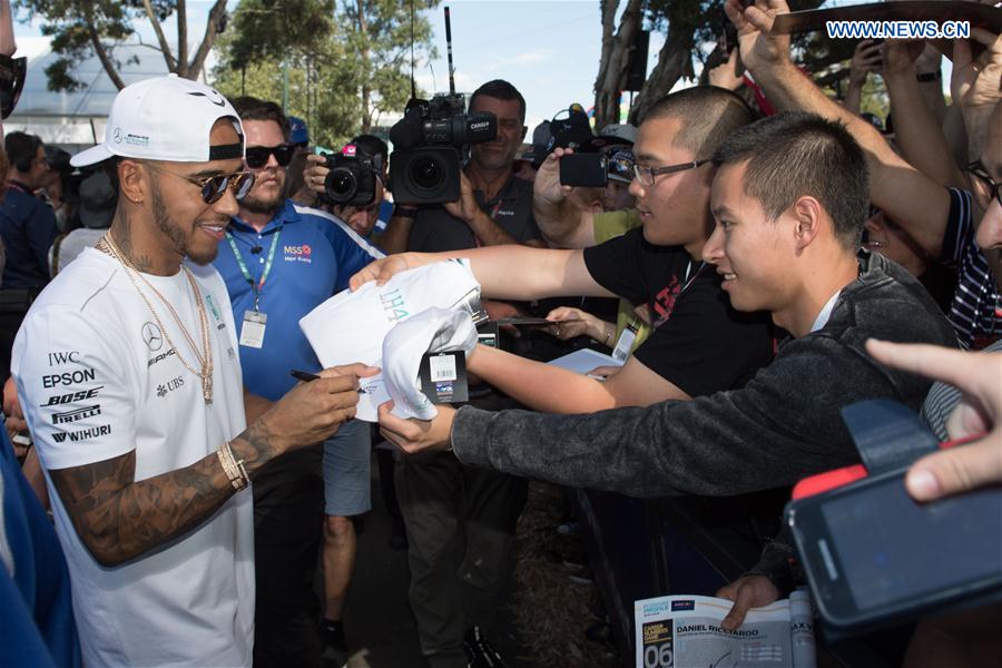Mercedes AMG Petronas Formula One driver Lewis Hamilton(L) of Britain signs autographs for his fans as he arrives for the third practice session ahead of the Australian Formula One Grand Prix at Albert Park circuit in Melbourne, Australia on March 25, 2017. 