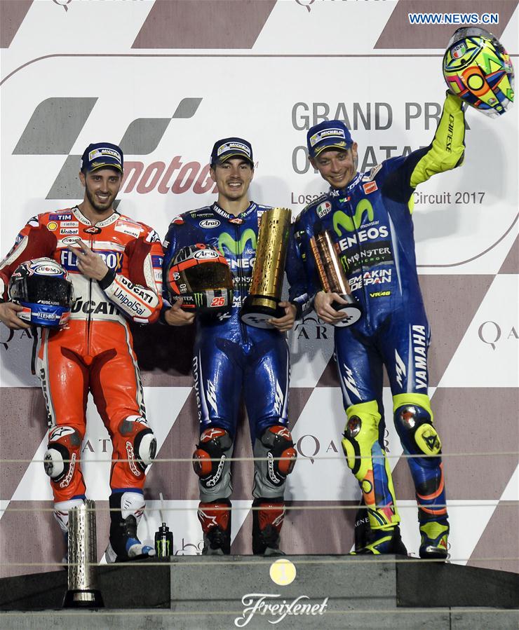 Movistar Yamaha MotoGP's Spanish rider Maverick Vinales (C) poses with Ducati Team's Italian rider Andrea Dovizioso (L) and Movistar Yamaha MotoGP's Italian rider Valentino Rossi during the awarding ceremony for the 2017 FIM MotoGP Grand Prix of Qatar at the Losail International Circuit in Doha, capital of Qatar, on March 26, 2017. 