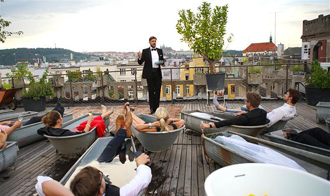 Audience watch performance in hot tubs on roof of building in Prague