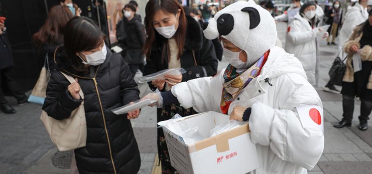 Members of volunteer group distribute free masks to local people in Tokyo