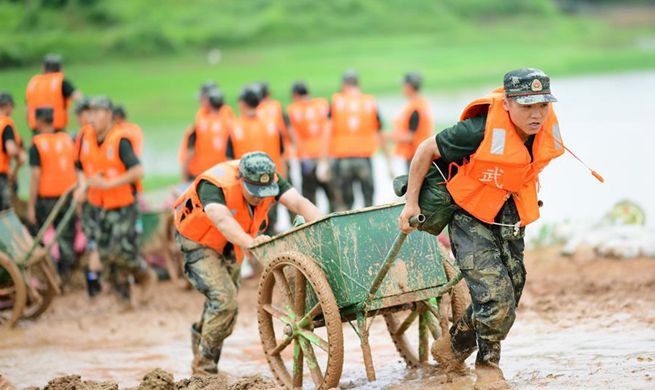 Armed policemen move sand bags for dyke reinforcement in Poyang County, Jiangxi