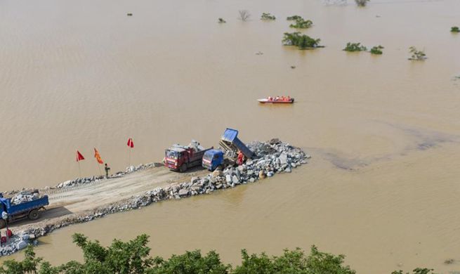Staff members work at construction site of breached dyke in Poyang Town