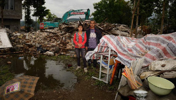 Family photos taken in front of dismantled houses in quake-hit Lushan, SW China