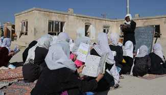 Afghan girls read books in open-air class