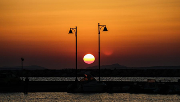 Tourists watch sunset at Portara on Naxos island in Greece