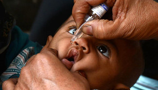 Pakistani health worker gives polio vaccine to child on World Polio Day