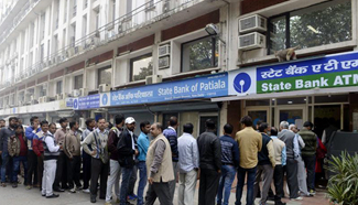 People queue outside banks to withdraw cash in India