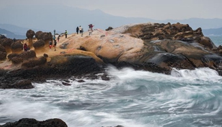 Tourists watch sea waves at Yehliu Geopark in New Taipei City
