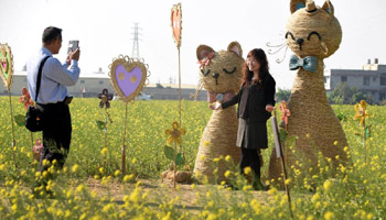 Visitors pose for photos with statues made of straw in China's Taiwan