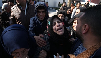 People wait to receive remains of three Palestinians at Rafah border