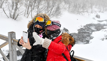 Tourists walk against snow at Changbai Mountain