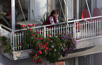 Greeks enjoy sunshine at balconies amid COVID-19 epidemic