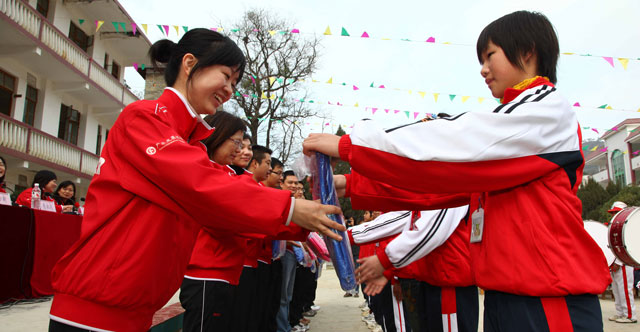 2009年12月，广发希望慈善基金的志愿者来到了广西德保县。图为志愿者给孩子送书包。