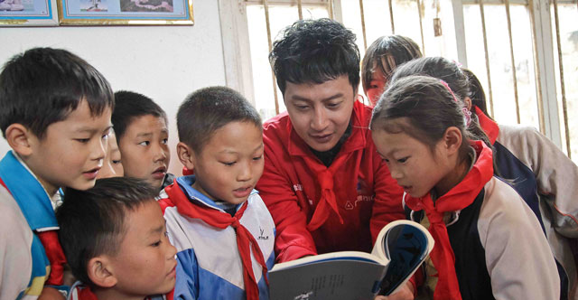 2012年10月，广发志愿者们远赴贵州省独山县和平塘县。图为爱心大使陈志明与孩子读书。