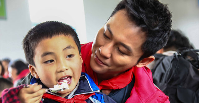 2013年10月，广发志愿者们前往湖南省隆回县和城步县。图为爱心大使李晨为孩子做爱心午餐。