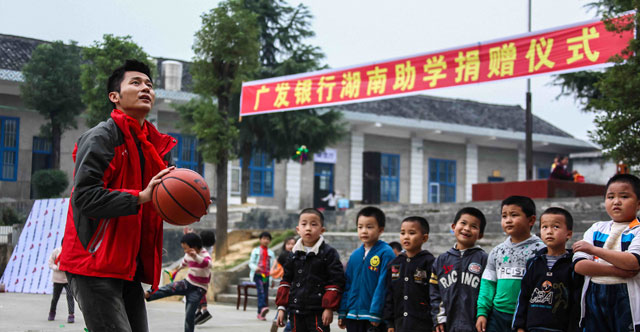2013年10月，广发志愿者们前往湖南省隆回县和城步县。图为爱心大使李晨与孩子一起篮球互动。