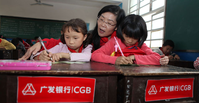2013年10月，广发志愿者们前往湖南省隆回县和城步县。图为志愿者为孩子辅导作业。