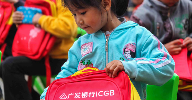 2013年10月，广发志愿者们前往湖南省隆回县和城步县。图为孩子领到漂亮小书包。