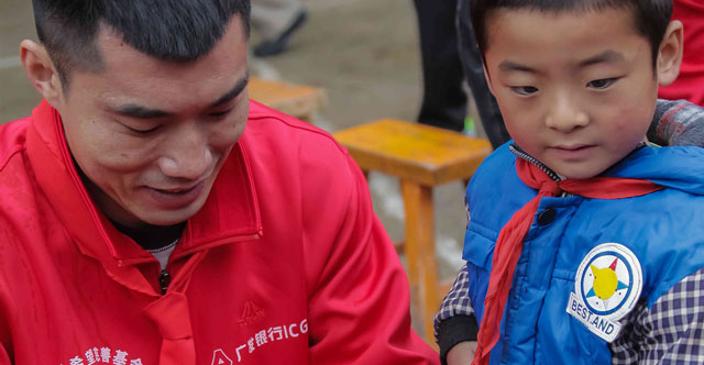 2014年9月，广发志愿者们前往甘肃省陇西县和平凉市。图为爱心大使郑智给孩子送书包。
