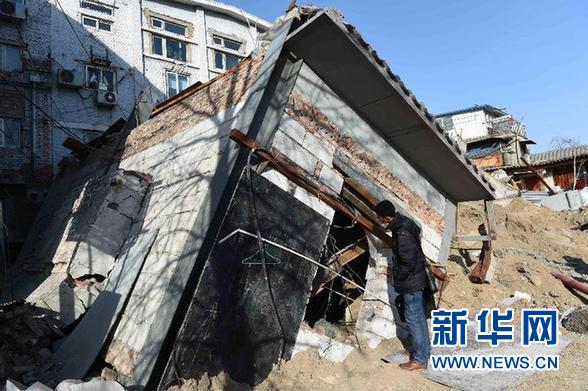 一名工作人员在北京市德内大街93号院塌陷现场查看倒塌的建筑