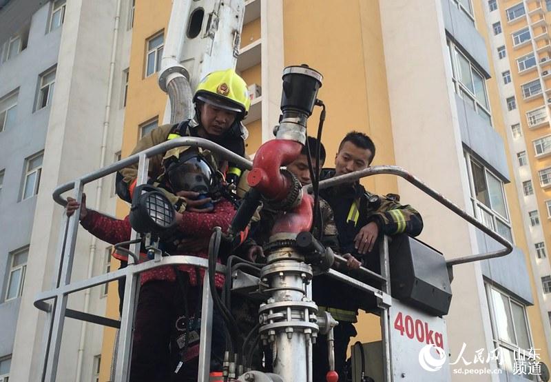 聊城市公安消防支队特勤中队指导员梁佃军（左一），在到达现场后的三十五分钟里，七次进入火场&ldquo;七进七出&rdquo;，连续救出五人。图为梁佃军把呼吸器面罩给了孩子。