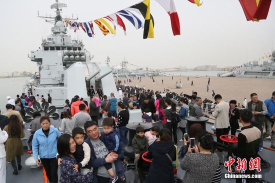 4月23日，中国人民解放军海军成立67周年纪念日，挂满旗的导弹驱逐舰哈尔滨舰停靠在青岛某军港码头向当地市民开放。与此同时，在旅顺某军港码头，导弹护卫舰葫芦岛舰也悬挂着象征节日最高礼仪的满旗对外开放。图为哈尔滨舰开放参观。